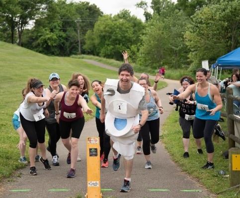 Fix a Leak Family 5K Event Pictures from 2019 of Runners trying to catch the toilet